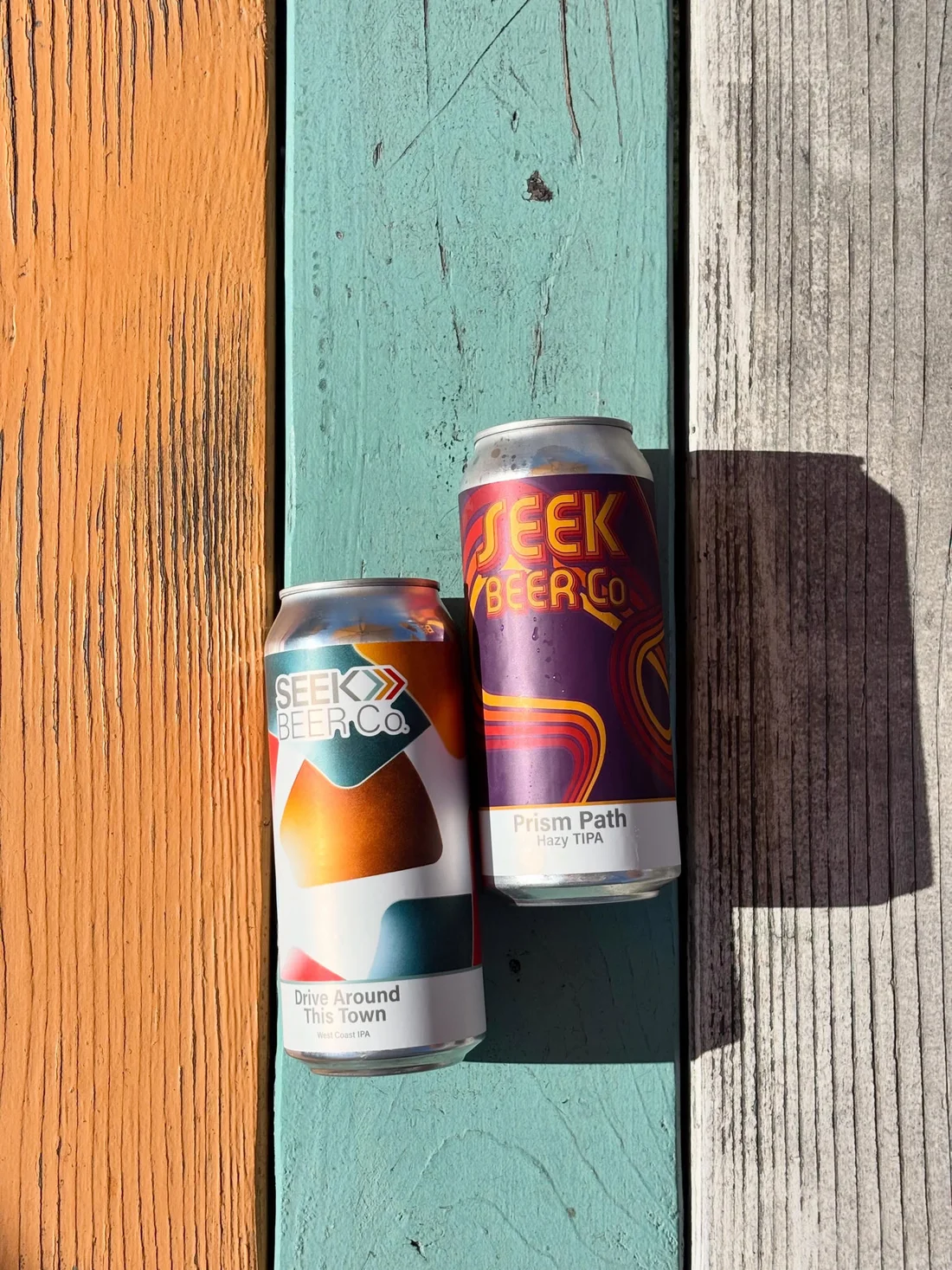 Drive Around This Town and Prism Path cans on painted wood