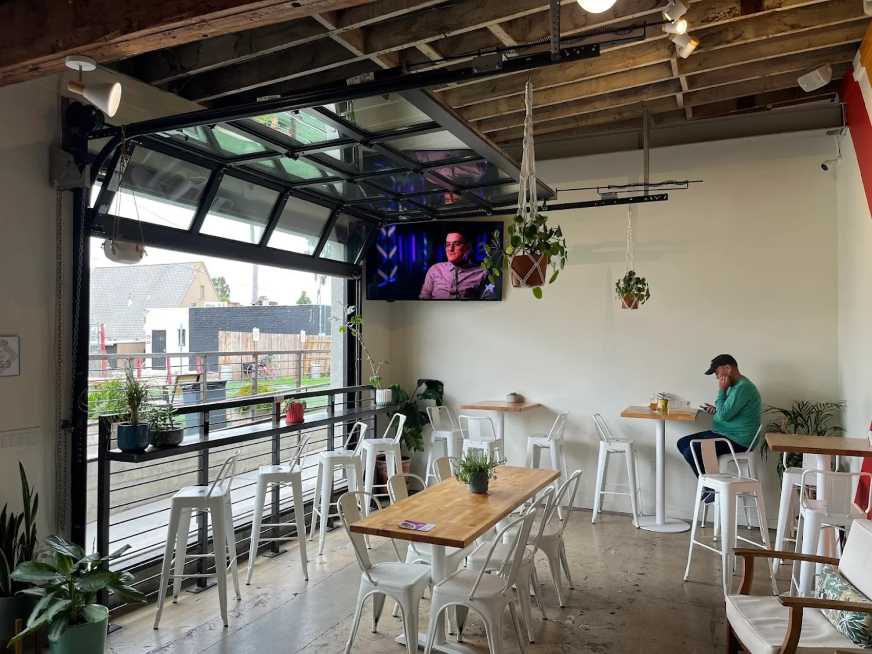 Garage doors rolled open at Seek Beer Co. with high-top tables and afternoon light